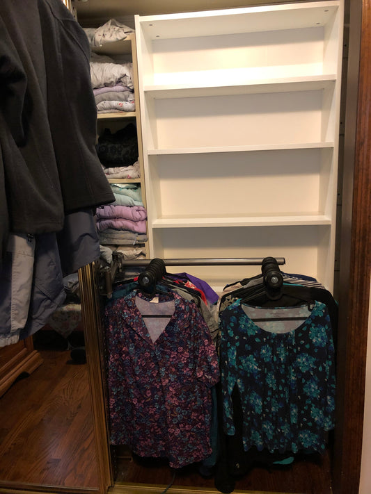 Image of an apartment closet showcasing the Be Clever Closet Rod System with clothes organized on multiple levels and shelves.